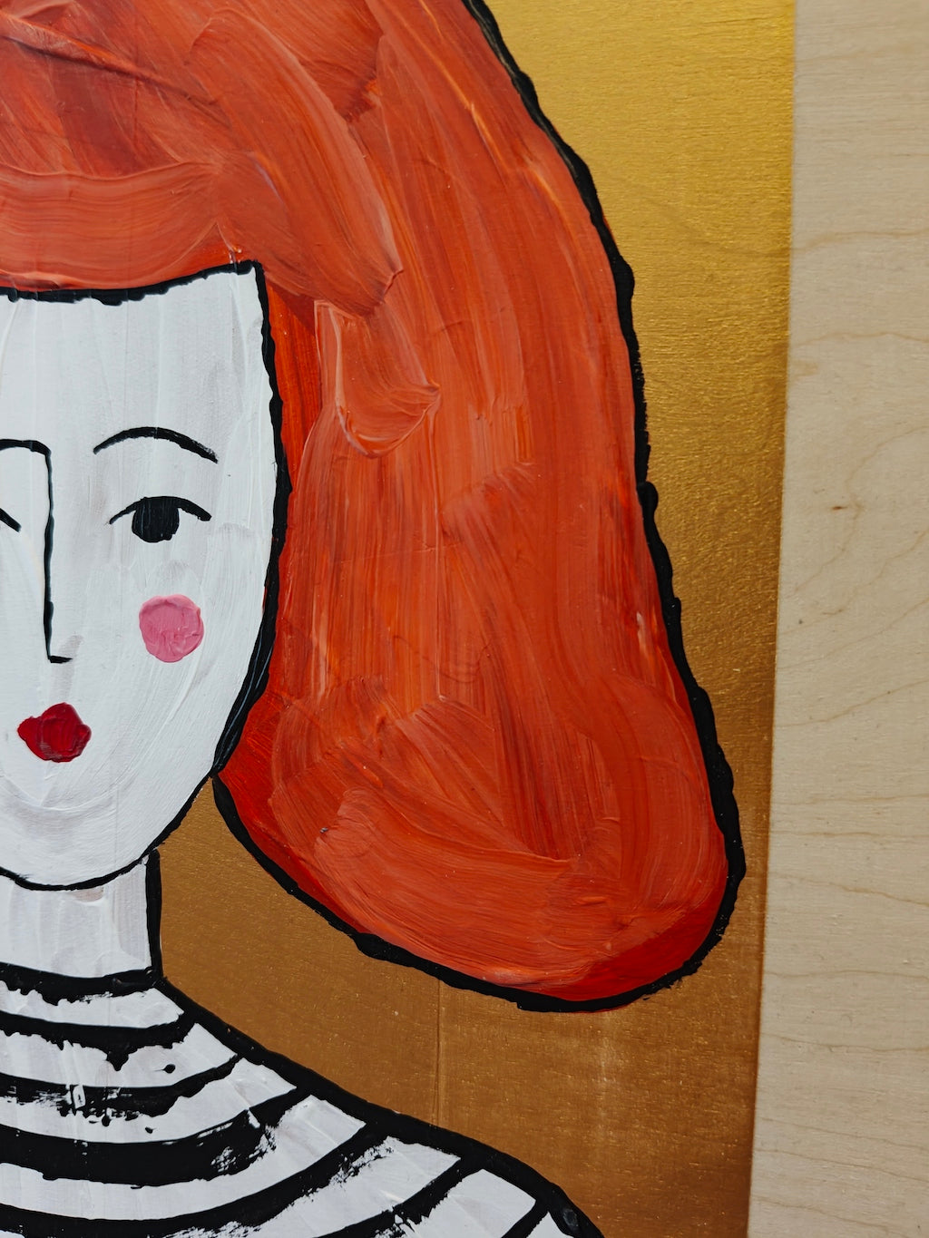 Close up of acrylic paint on birch plywood depicting a woman with bright orange hair, against a gold backdrop. She's wearing a black and white striped top.