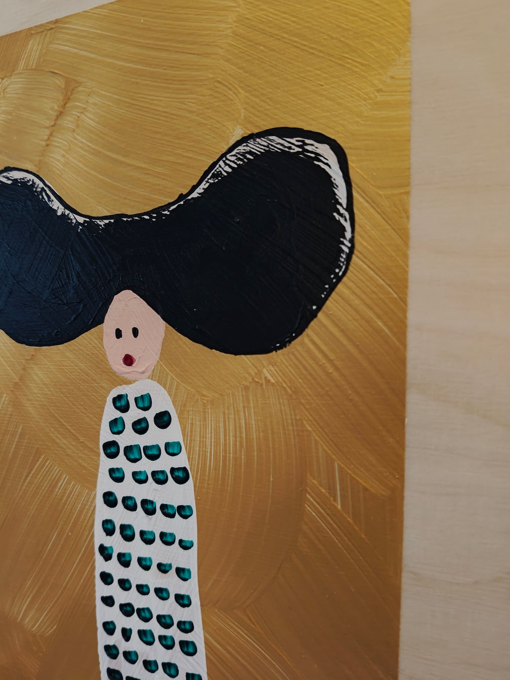 Close up of Acrylic painting on birch plywood depicting a woman with large black hair against a gold backdrop. She's wearing a white dress with green dots.