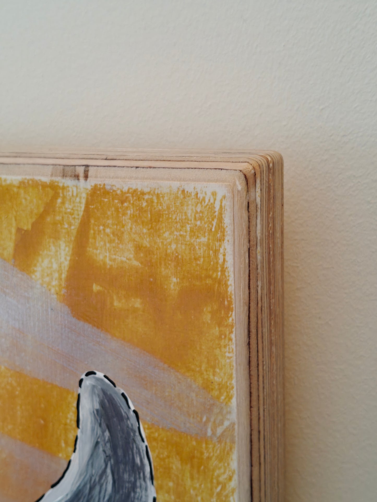 Close up of the corner of a Pop art painting of a woman with large flyaway hair and a black dress with silver spots on. The background of the painting is silver and yellow.