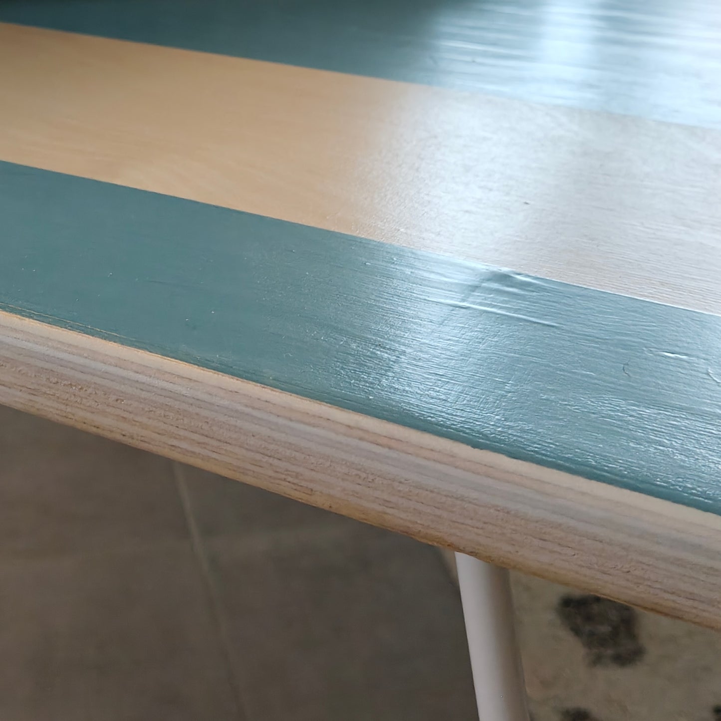Close up view of Plywood coffee table with hand-painted unique design in blue and white. White metal hairpin legs.