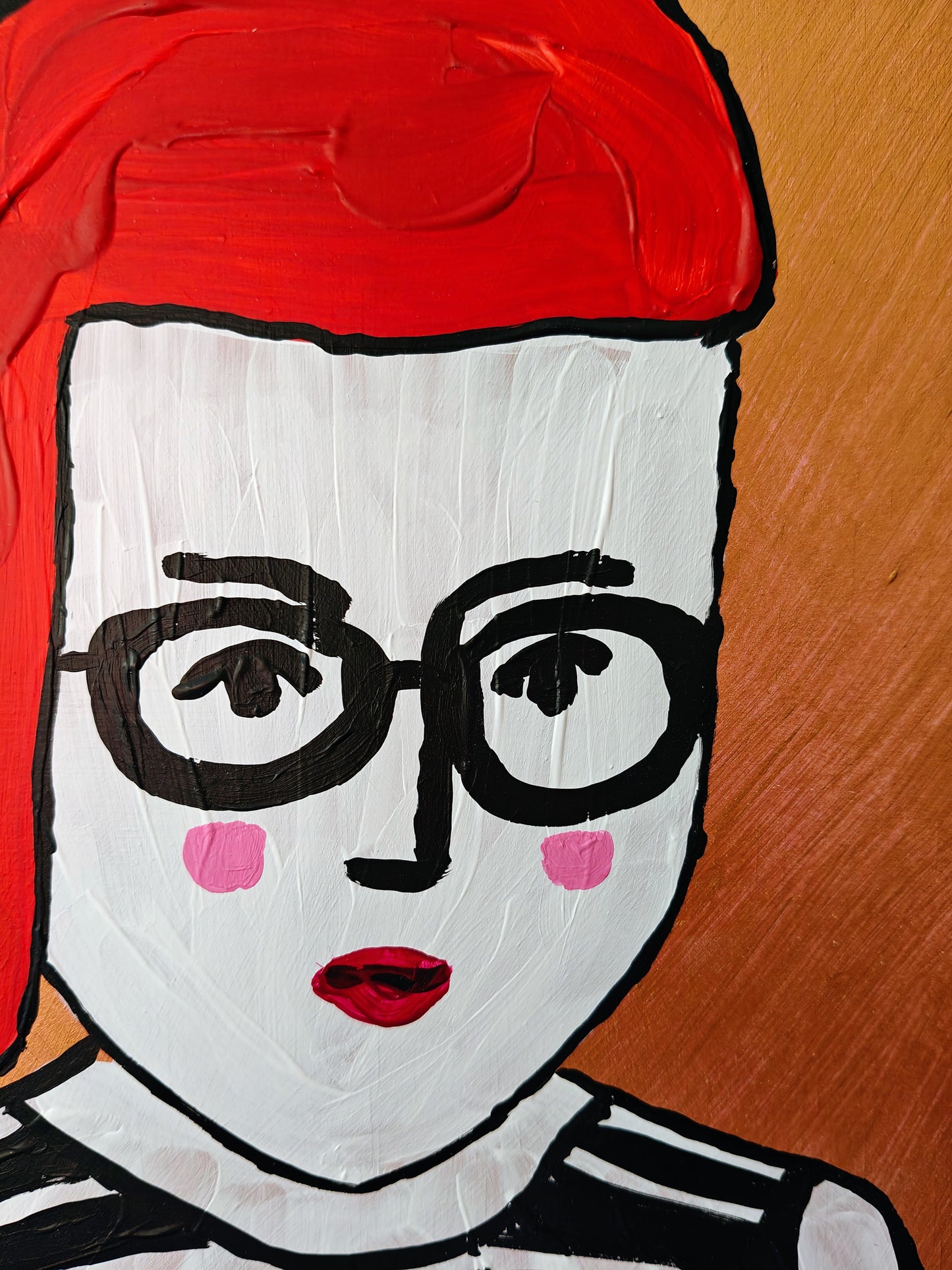 Close-up of A colorful painting of a woman with red hair, black glasses, and a striped top, set against a gold metallic background.