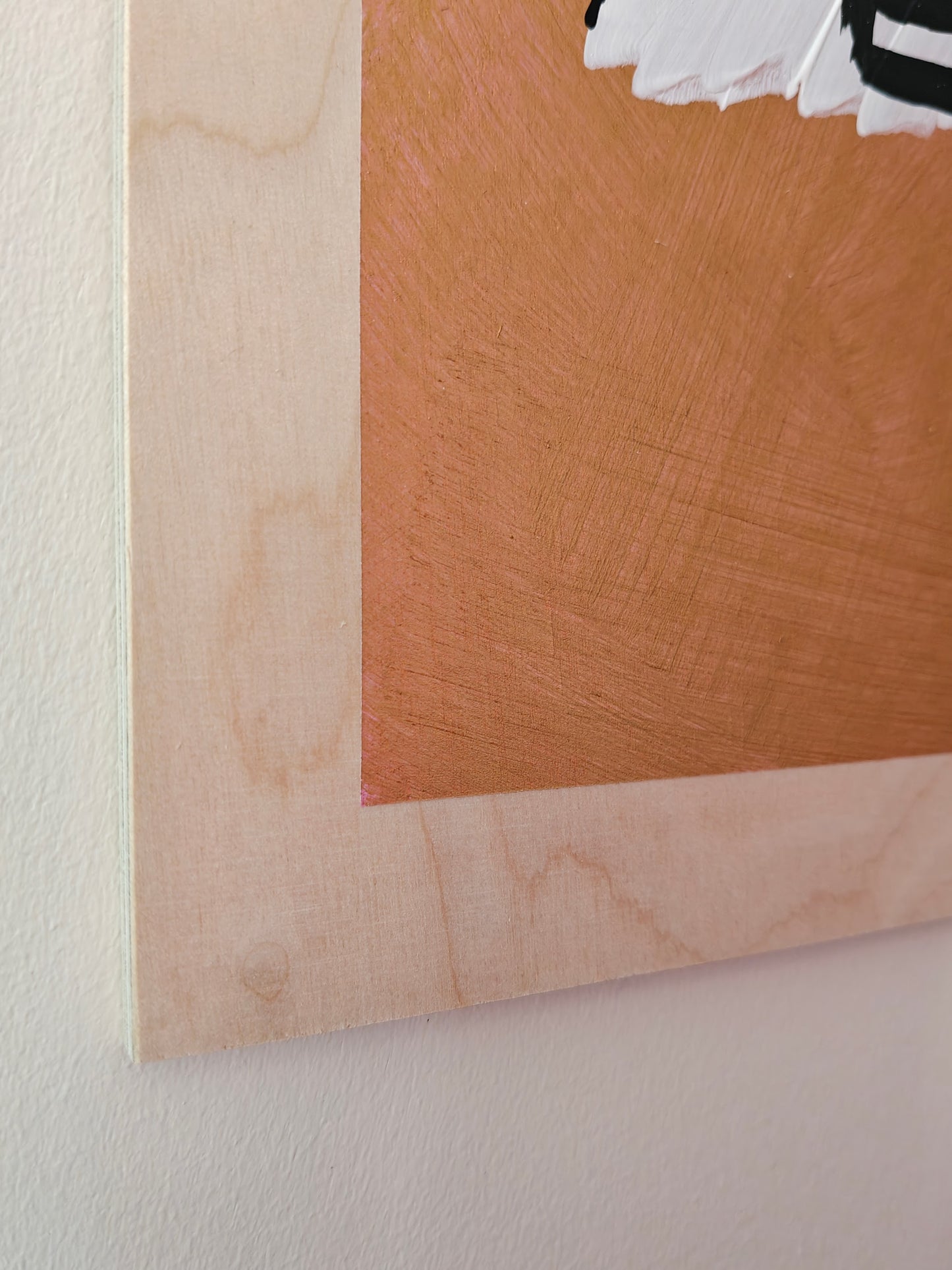 Close-up of the corner of a painting of a woman with red hair, black glasses, and a striped top, set against a gold metallic background, painted on light coloured natural plywood.