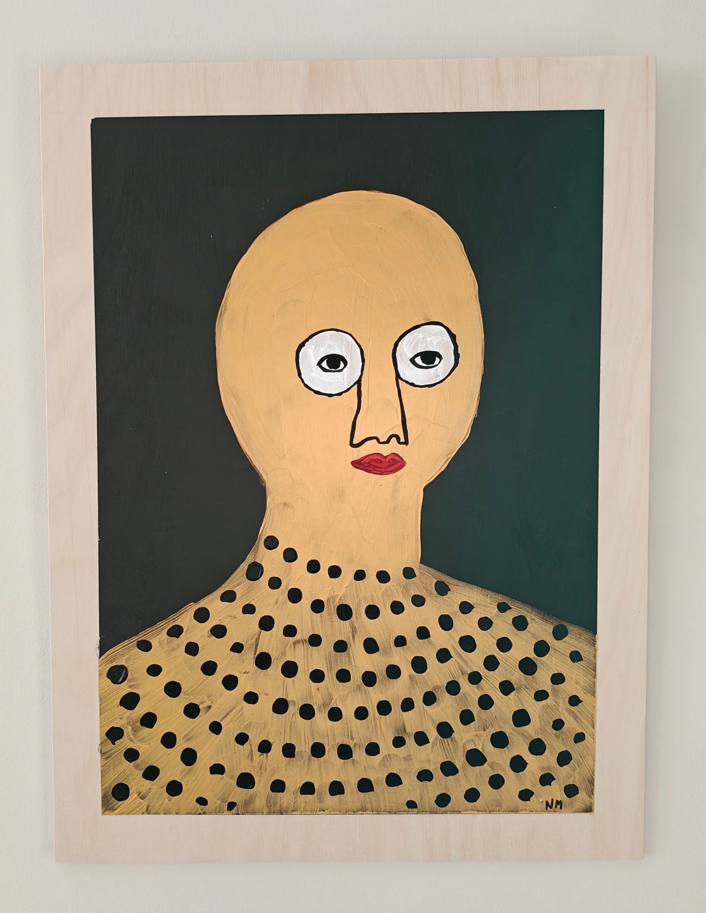 Pop art portrait of a character in gold, with black spots on their top. The character has red lips and large white eyes. The background of the painting is black. The painting is hung on a white wall.