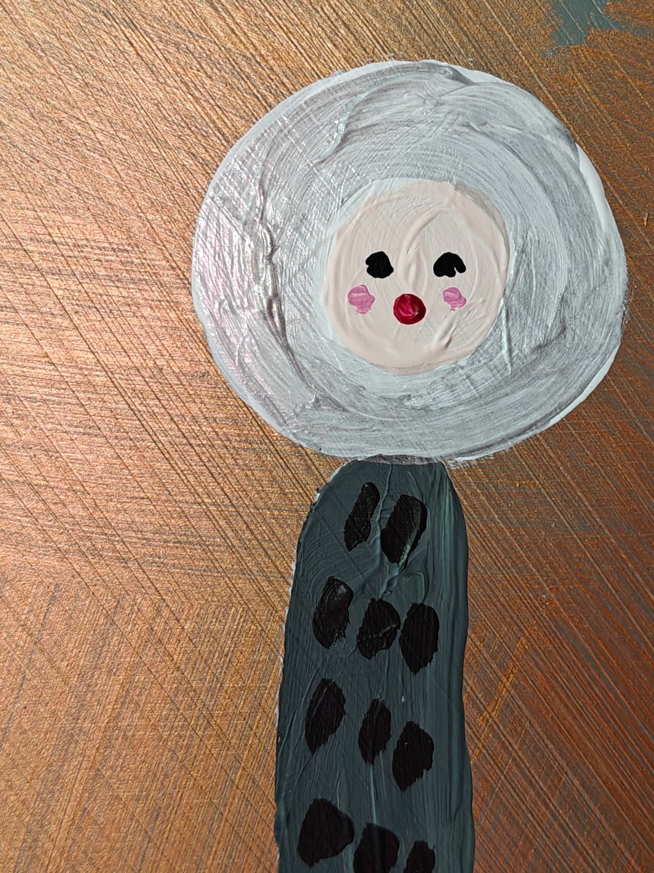 Detail view of A playful painting featuring two tall, abstract figures with dotted bodies and round, expressive faces. The background has a metallic copper tone, contrasting with the natural plywood that the image has been painted on. Part of the Life in Colour collection.